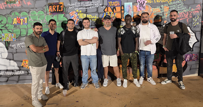 Eine Gruppe Männer steht vor einer Graffittiwand